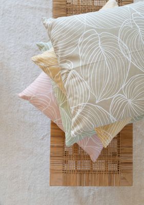 Tilda kuddfodral i gult, beige, grönt och rosa staplade på stol