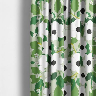Detaljbild på gröna gardiner med vita blommor och blad i olika gröna nyanser