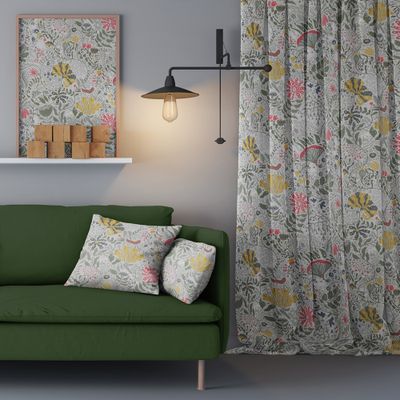 En mysig inredningsdetalj med Myllra gröna gardiner med levande blomstermönster, bredvid en matchande grön soffa och en stämningsfull vägglampa, som skapar en inbjudande och harmonisk atmosfär.