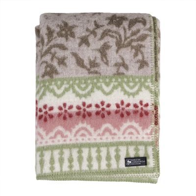 Kerstin Landström Design Torpet ullfilt i naturfärgad ull med dekorativt mönster i grönt och rött, vikt mot ljus bakgrund.