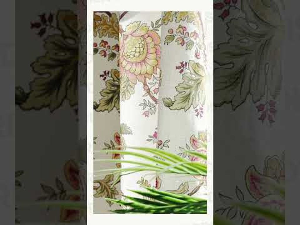 Video som visar en gardin ur kollektionen Heritage med ett detaljrikt, blommigt mönster i dova nyanser. Gardinen faller mjukt i ett ljust fönster, med grön växt som skapar en harmonisk och hemtrevlig känsla.