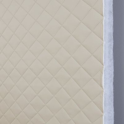 Närbild på ljusbeige fuskskinn med vadderad baksida och diagonalrutigt mönster, ca 5x5 cm per ruta. Hög slitstyrka, 45 000 Martindale.