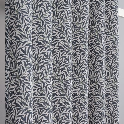 Närbild på Ramasino blå som visar det detaljrika arts and crafts-inspirerade mönstret med blå blad, gröna grenar och ljus botten.