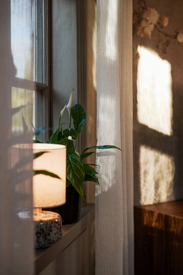 Närbild av Brooke offwhite gardin från Jakobsdals vid ett fönster, med mjukt solljus som framhäver gardinens tunna väv och struktur.