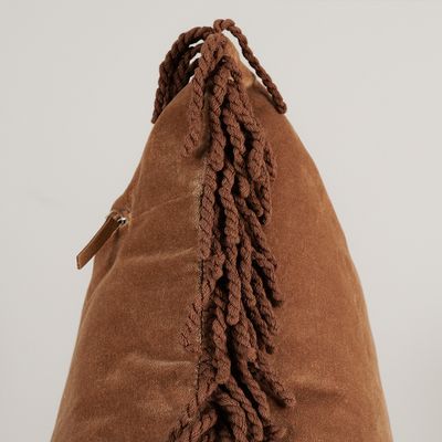 Närbild från sidan av Frill beige kuddfodral som visar sammetsytan och den dekorativa tvinnade fransen.
