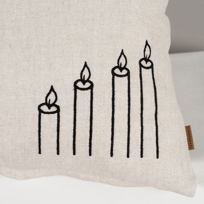 Närbild på Glow kuddfodral i beige bomulls- och linnemix med svart broderi föreställande fyra tända ljus.
