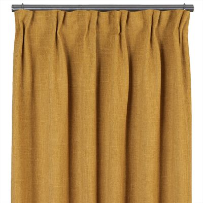 Ockragul 100% mörkläggningsgardin med fyllig vävd struktur upphängd på gardinstång.