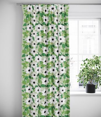 Gröna blommönstrade gardiner som hänger framför ett fönster i ett ljust rum