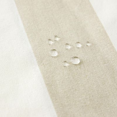 Närbild av Striato beige randig vaxduk med vattendroppar på den vattenavvisande ytan.