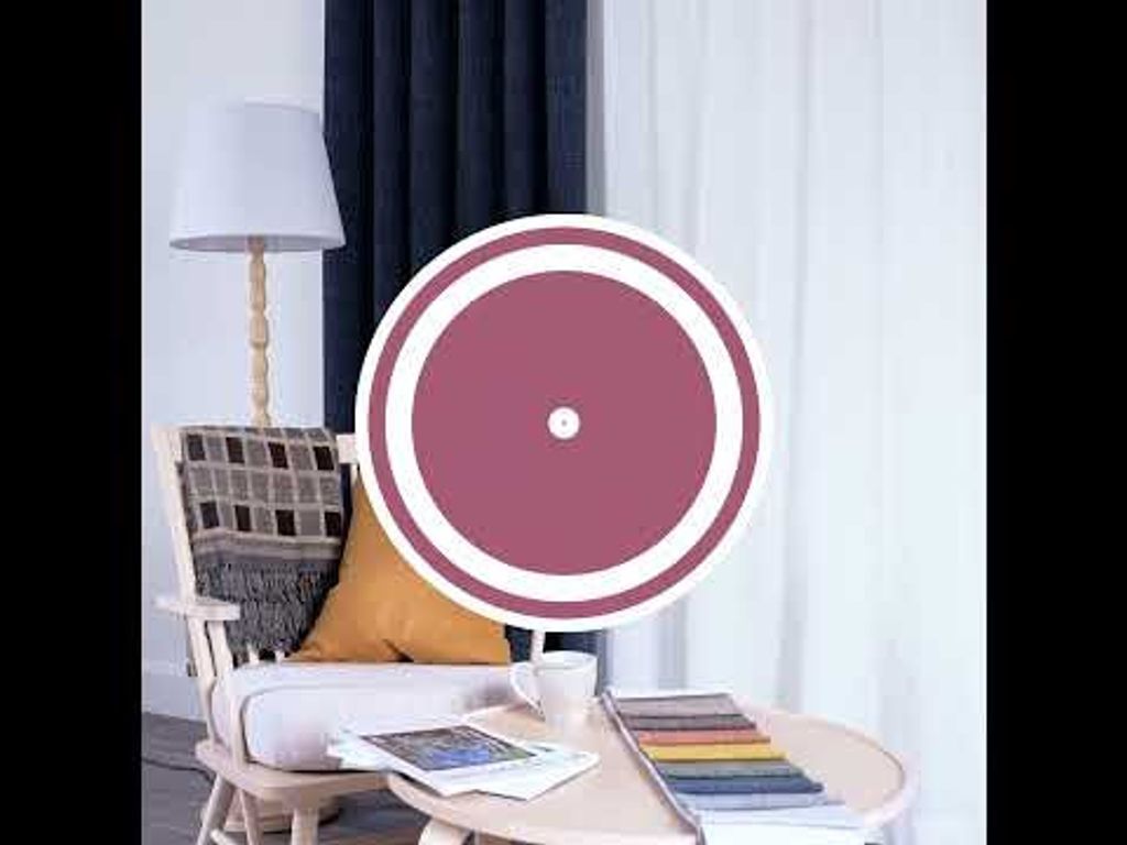 Video med långsam panorering i vardagsrumsmiljö med Cru blå mörkläggningsgardin, ljus träfåtölj med kudde och pläd, kaffekopp med lätt ånga och tygprover på runt bord.