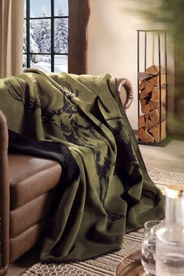 Grön filt med hjortmotiv över fåtölj i vardagsrum