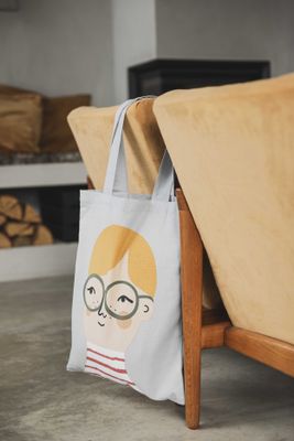 Ljusgrå tygkasse med motiv av Pim som hänger över en fåtölj i ett vardagsrum