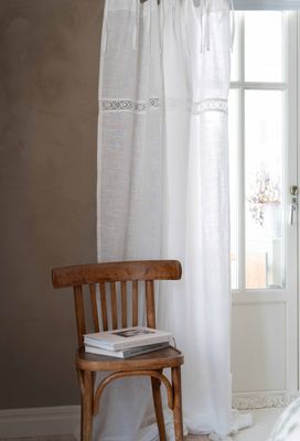 Sanna 2-pack gardinlängder med knytband och en dekorativ spets upphängd vi en balkongdörr