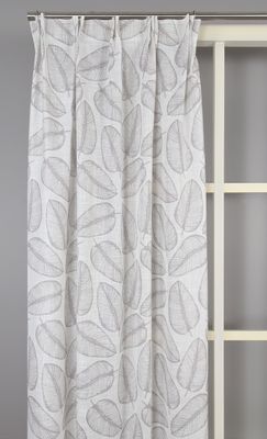 Sienna beige gardin upphängd i rumsmiljö, visandes dess ljusgenomsläppliga tyg och dekorativa fall
