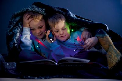 Barn som läser bok tillsammans under Cosmos filt med rymdmotiv