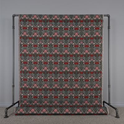 Rullad gobeläng metervara med klassiskt mönster av blad och blommor i rött och rosa på en mörk bakgrund, OEKO-TEX Standard 100 klass II-certifierad.