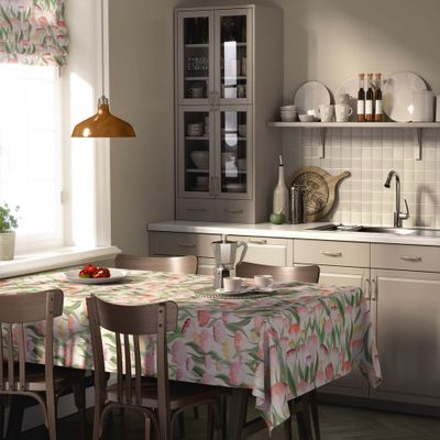 Ljuvlig rosa bordsduk dukad på ett matbord i kök med blommigt mönster i rosa, aprikos och gröna nyanser