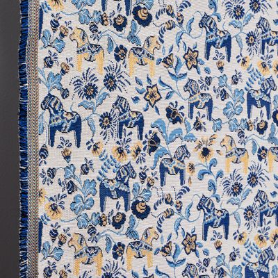 Närbild av jacquardvävd gobeläng med dalahästar i blått och gult samt synlig vävstruktur och kant.