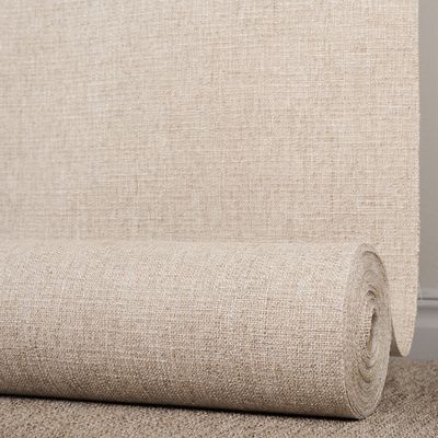 Möbeltyget Coco beige sand från Safeco på rulle framför en upphängd längd av samma tyg, som visar tygets ljusa melerade struktur.