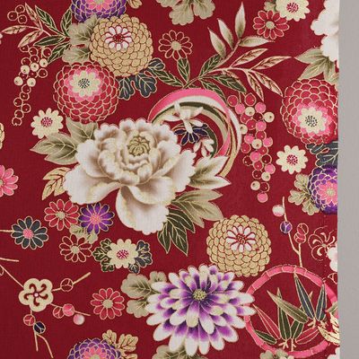 Detaljbild av Chihiro röd med stor cremevit blomma, rosa och lila blommor samt gröna blad och guldfärgade dekorationer.