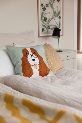 Agda ett kuddfodral med hundmotiv ligger på en bäddad säng