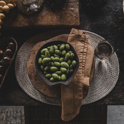 Oval bordstablett i naturfärgad jute med tallrik och skål i rustik dukning.