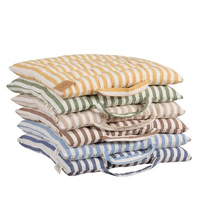 Samlingsbild av Svea sittdynor i sex olika färger staplade ovanpå varandra. Dynorna har ett randigt mönster i vitt tillsammans med gula, gröna, beige, bruna och blå toner samt praktiska bärhandtag i matchande färger.