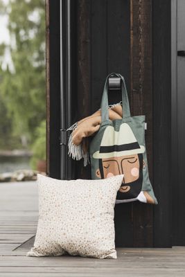 Grön tygkasse med motiv av Max hänger på krok utomhus