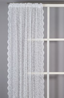 Ljus offwhite spetsgardin med blommigt mönster som släpper igenom dagsljus i fönster.