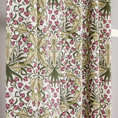 Rullad gardin med Willow Bloom-mönster i rosa och grönt uppställd mot en vägg, visar tygets struktur och fall.