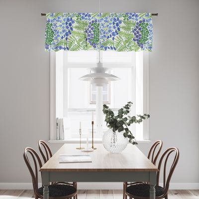 Gardinkappa med blå och gröna motiv upphängd i ett ljust kök ovanför fönster