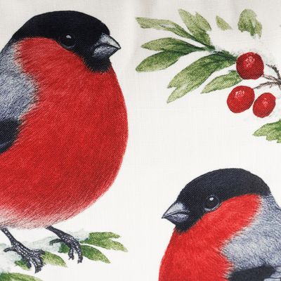 Närbild på kuddfodralets motiv med röda domherrar, gröna blad och röda vinterbär.