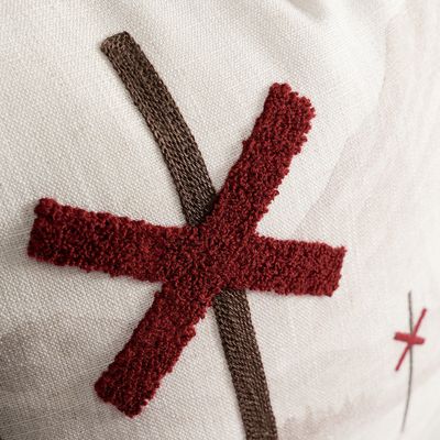 Närbild på rött broderat ledkryss och brun detalj på Ledkryss kuddfodral.