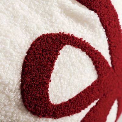 Närbild på mörkröd broderad rosett mot vit teddy på Paket kuddfodral