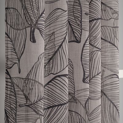 Detaljbild av Hugo beige/grön öljettgardin med gröna och svarta ritade blad fotad från sidan
