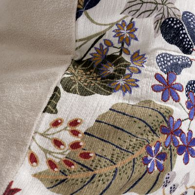 Detaljbild av Laura kuddfodral där tryckta blad och broderade blommor möter den mjuka teddybaksidan.