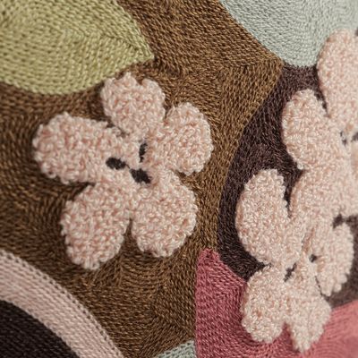 Detaljbild av broderade blommor på Monique vinröd kuddfodral med struktur och relief.