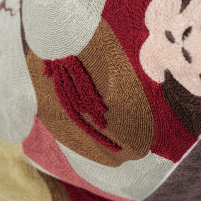 Närbild på broderade blad och organiska former i vinröda och jordnära färgtoner på Monique kuddfodral.