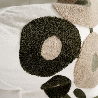 Närbild av mörkgrön broderad blomma på Sabina kuddfodral som visar den mjuka och strukturerade ytan.