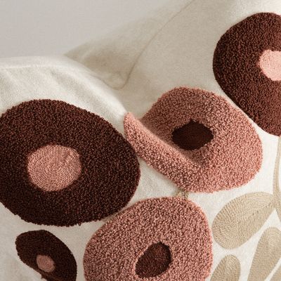 Närbild på Sabina rosa kuddfodral som visar de upphöjda broderade blomformerna och den mjuka teddyytan.
