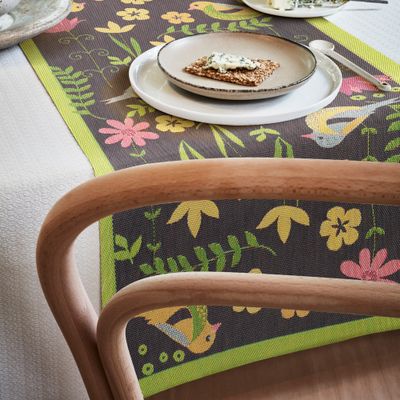 Svenskdesignad, hållbar bordslöpare med ett lekfullt naturinspirerat mönster på en mörk bakgrund, framställd enligt GOTS-standarder.