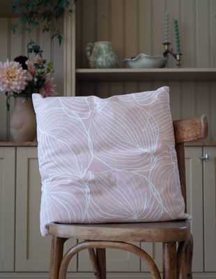 Rosa Tilda kuddfodral med vitt mönster på trästol