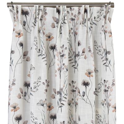 Liora gardin upphängd på stång, visad framifrån med blommigt akvarellmönster i naturnära toner.