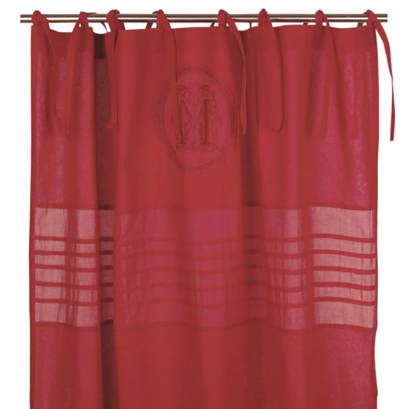 Rösa gardiner med knytband och ett dekorativt monogram i mitten