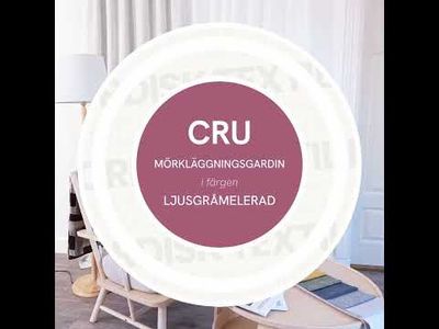 Produktvideo med långsam panorering som visar Cru ljusgråmelerad mörkläggningsgardin i dubbelbredd i en ljus miljö med fåtölj, kudde, pläd och tygprover på bord.