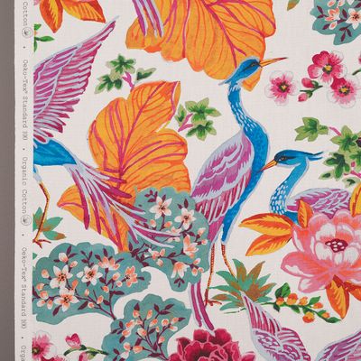 Närbild av Whispers tyg som visar detaljer av tranor, blommor och exotiska blad i klara färger.