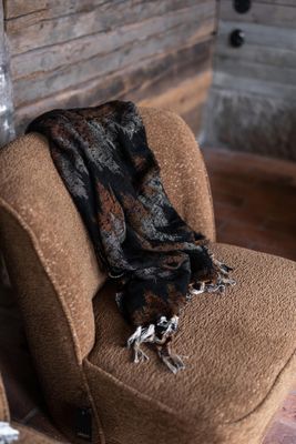 Mönstrad Aurora pläd draperad över brun fåtölj i varm och rustik inredning