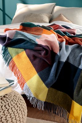 Färgglad rutig filt över säng i modernt sovrum