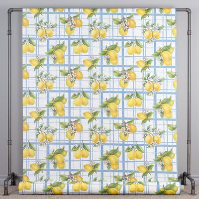 Hel vy av citronmönstrad textilvaxduk upphängd på ställning som visar hela mönstret.
