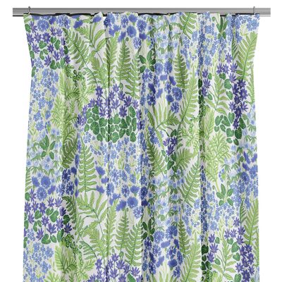 Närbild på gardin med blå och lila blommor samt gröna blad mot ljus botten